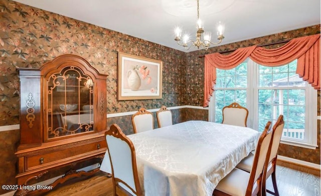 dining area with a healthy amount of sunlight, a notable chandelier, and hardwood / wood-style flooring