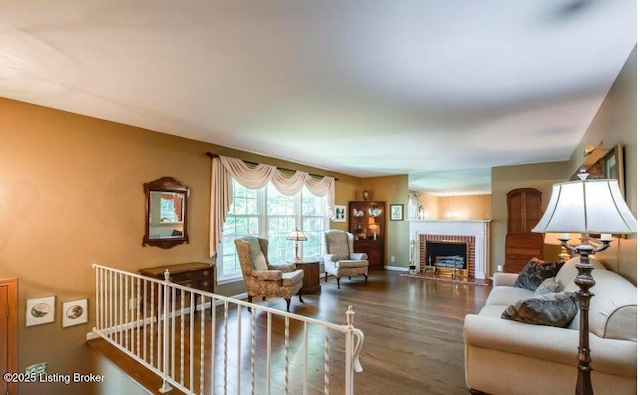 living room featuring wood-type flooring and a brick fireplace