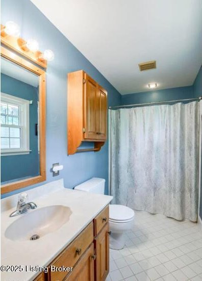 bathroom with curtained shower, tile patterned flooring, vanity, and toilet