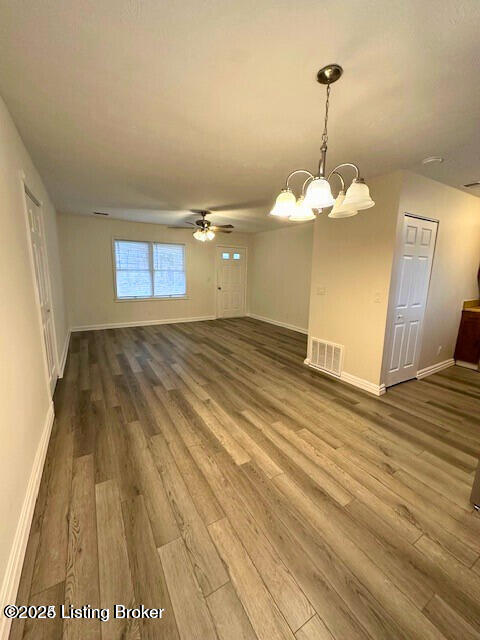 interior space with ceiling fan with notable chandelier and wood-type flooring