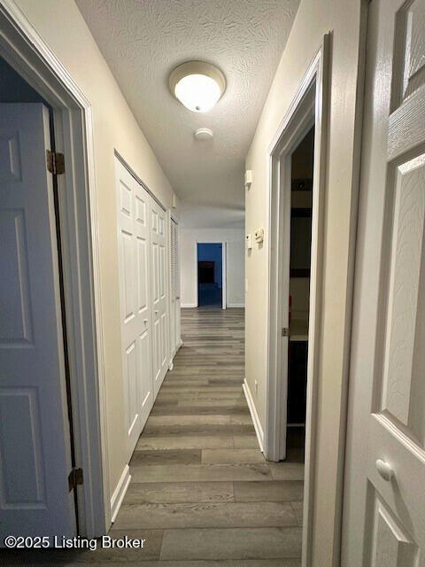 hallway with dark hardwood / wood-style flooring and a textured ceiling