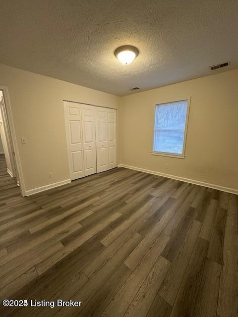 unfurnished bedroom with a closet, dark hardwood / wood-style floors, and a textured ceiling