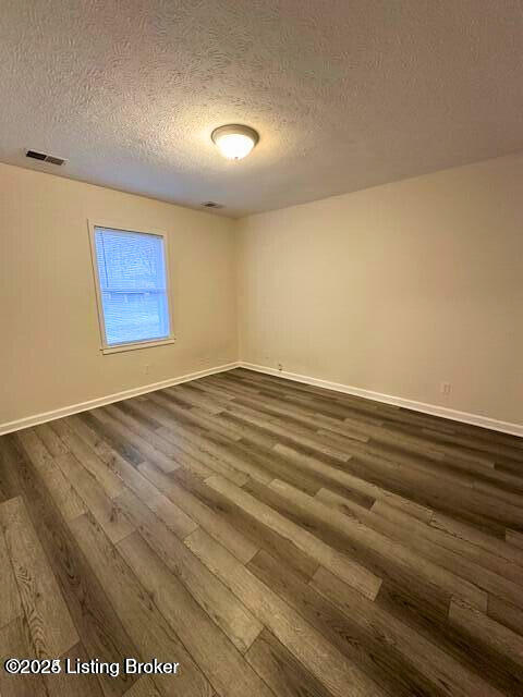 unfurnished room with dark hardwood / wood-style flooring and a textured ceiling