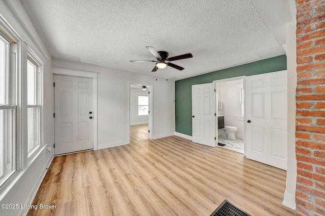 foyer with light hardwood / wood-style flooring, a textured ceiling, a wealth of natural light, and ceiling fan