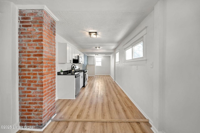 hall with sink, a textured ceiling, and light hardwood / wood-style flooring