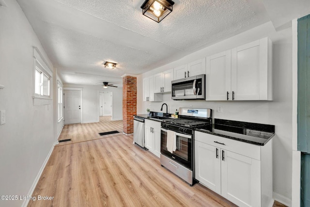 kitchen with ceiling fan, stainless steel appliances, sink, and white cabinets