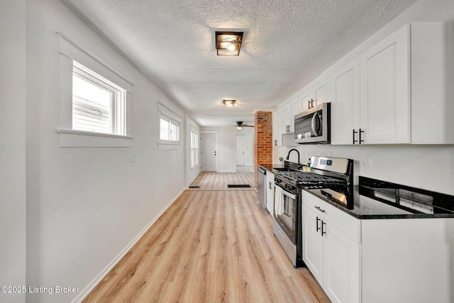 kitchen with light hardwood / wood-style flooring, ceiling fan, dark stone countertops, stainless steel appliances, and white cabinets