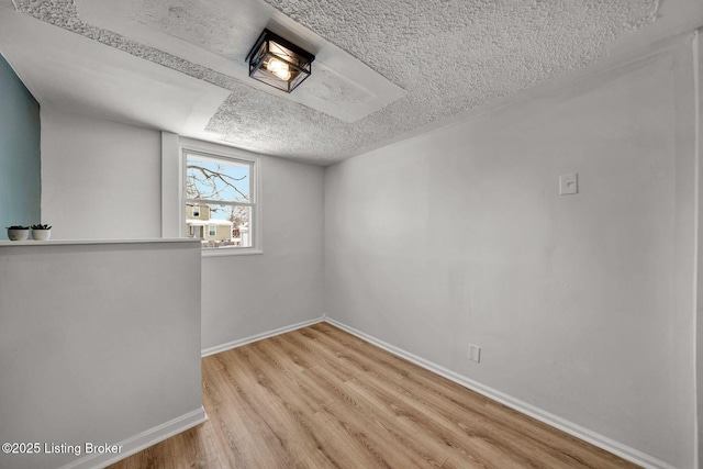 empty room with a textured ceiling and light wood-type flooring