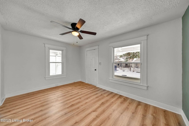 empty room with plenty of natural light, a textured ceiling, ceiling fan, and light hardwood / wood-style floors