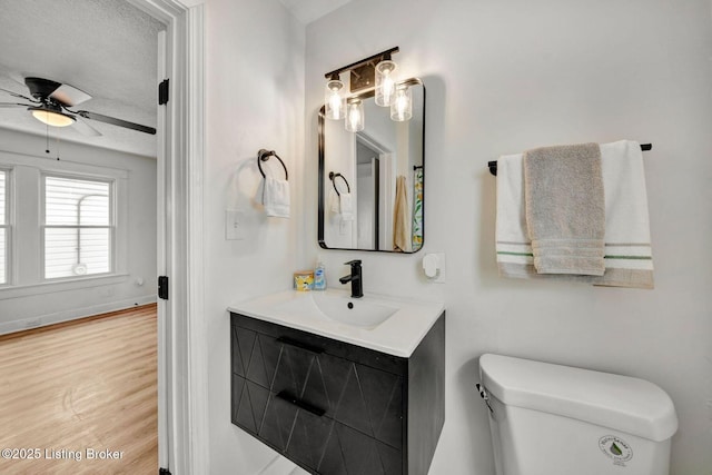 bathroom featuring toilet, a textured ceiling, vanity, hardwood / wood-style flooring, and ceiling fan