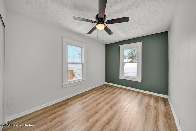 empty room featuring ceiling fan, a textured ceiling, and light wood-type flooring