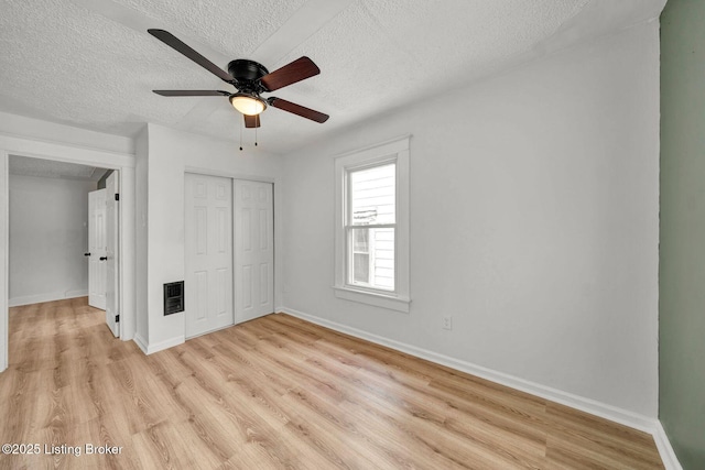 unfurnished bedroom featuring light wood-type flooring, a textured ceiling, ceiling fan, and a closet