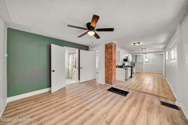 workout room featuring a textured ceiling, ceiling fan, and light wood-type flooring