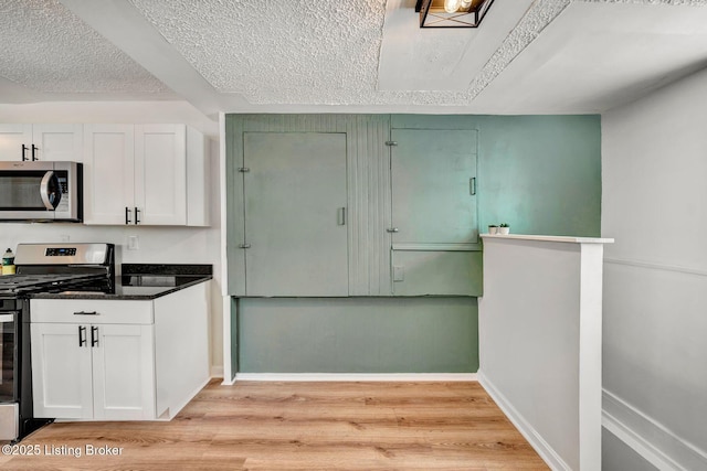 kitchen featuring stainless steel appliances, light wood-type flooring, a textured ceiling, and white cabinets