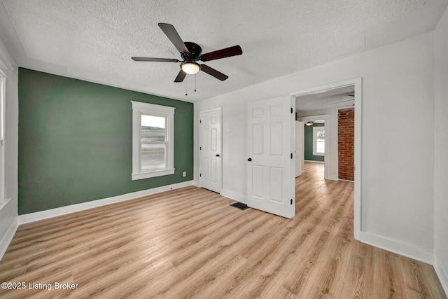 unfurnished bedroom featuring a textured ceiling, ceiling fan, and light wood-type flooring