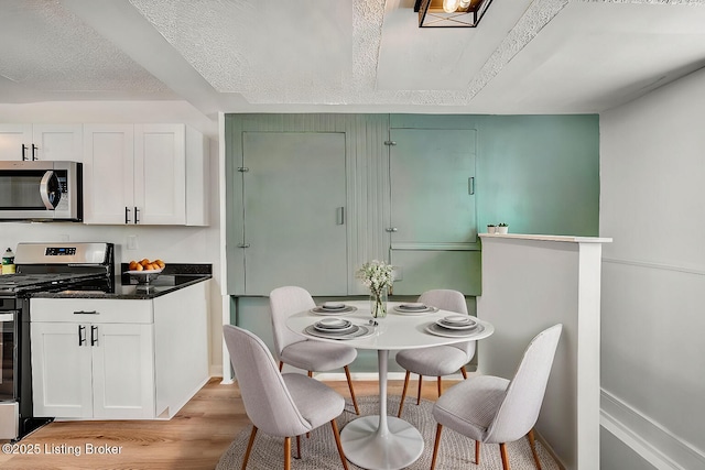 dining space featuring a textured ceiling and light hardwood / wood-style flooring