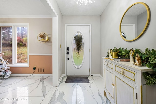 entrance foyer featuring crown molding, a textured ceiling, a wealth of natural light, and a chandelier