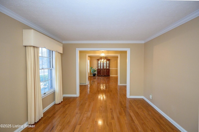 hallway with an inviting chandelier, crown molding, a textured ceiling, and light hardwood / wood-style floors