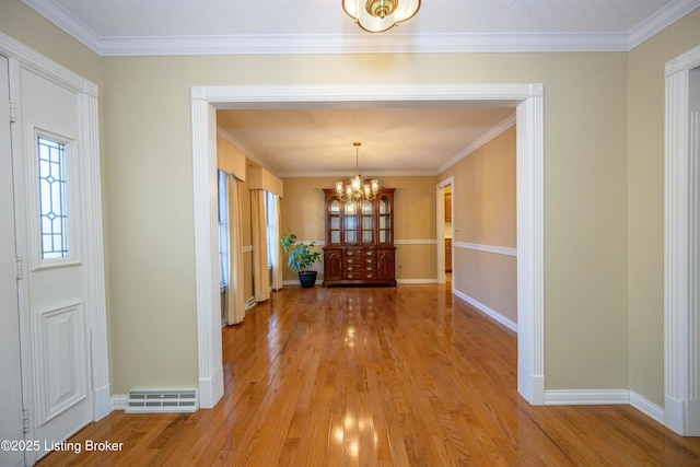 interior space with an inviting chandelier, crown molding, and light hardwood / wood-style floors