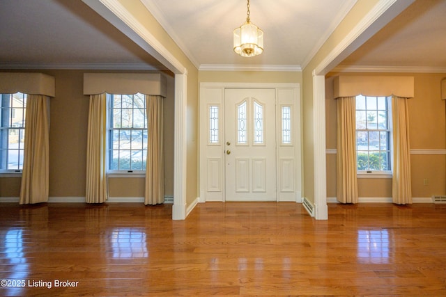 foyer featuring crown molding, a healthy amount of sunlight, hardwood / wood-style floors, and a notable chandelier