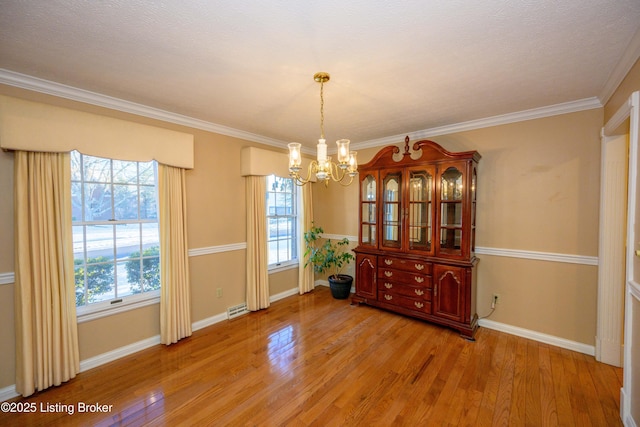 unfurnished dining area with light hardwood / wood-style flooring, ornamental molding, and an inviting chandelier