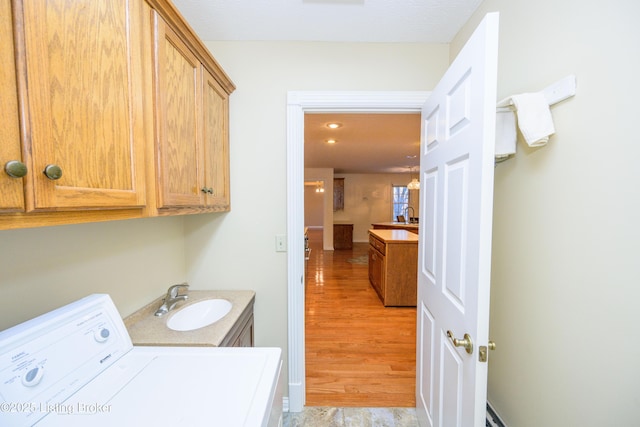 washroom featuring cabinets, sink, washer / dryer, and light hardwood / wood-style floors