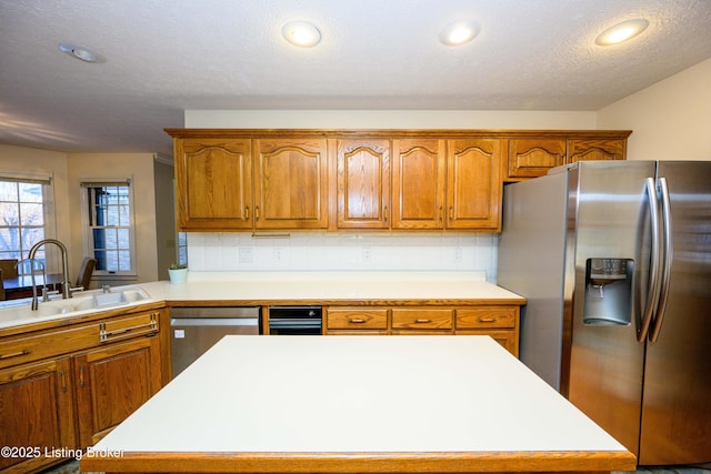 kitchen with appliances with stainless steel finishes, sink, a textured ceiling, and a kitchen island