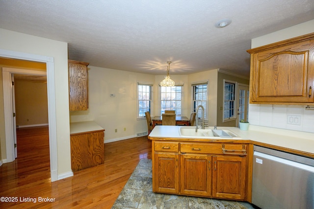 kitchen with a textured ceiling, dishwasher, decorative light fixtures, sink, and kitchen peninsula