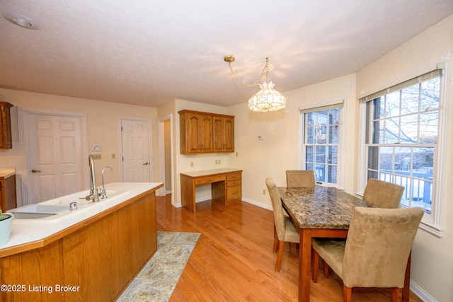 kitchen featuring decorative light fixtures, sink, a textured ceiling, and light wood-type flooring