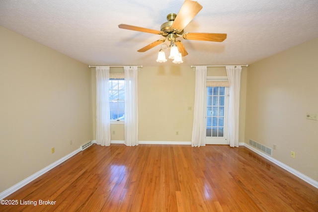 unfurnished room featuring light wood-type flooring, ceiling fan, and a textured ceiling