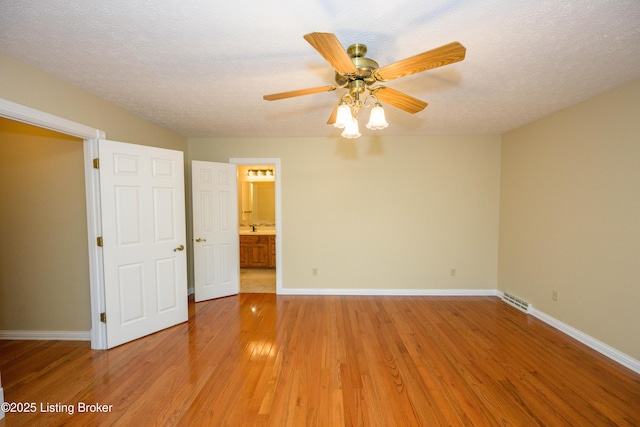 interior space featuring a textured ceiling, ceiling fan, ensuite bathroom, and light hardwood / wood-style floors