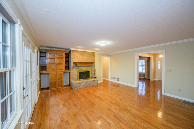 unfurnished living room featuring a brick fireplace, crown molding, a textured ceiling, and hardwood / wood-style flooring