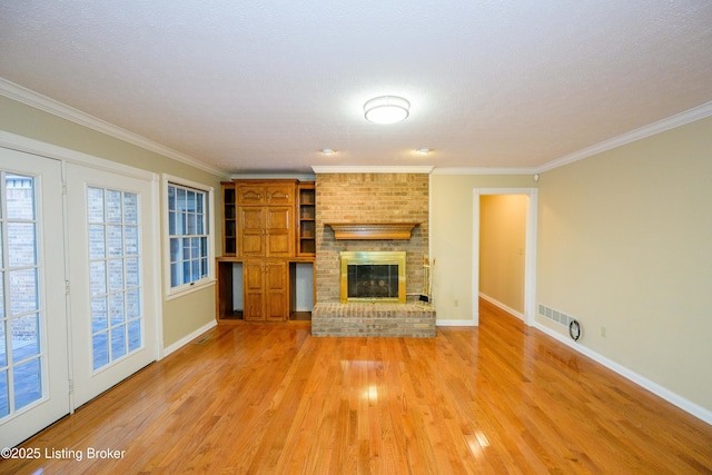 unfurnished living room featuring a brick fireplace, light hardwood / wood-style flooring, and crown molding