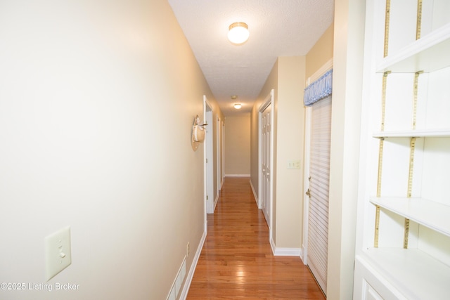 corridor with a textured ceiling and hardwood / wood-style flooring