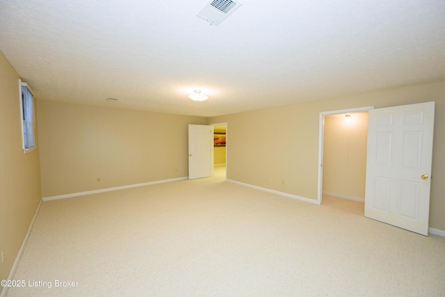 unfurnished room with light colored carpet and a textured ceiling