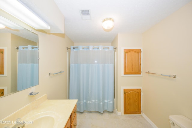 bathroom with toilet, vanity, and tile patterned flooring