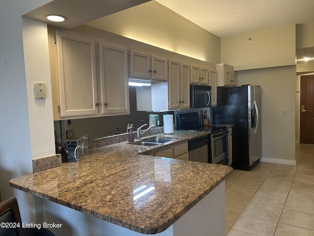 kitchen with sink, kitchen peninsula, stone countertops, light tile patterned flooring, and appliances with stainless steel finishes