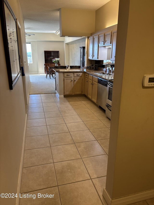 kitchen with kitchen peninsula, light brown cabinetry, light tile patterned floors, and appliances with stainless steel finishes