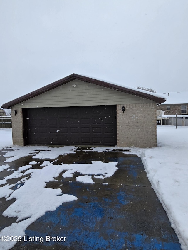 snow covered property with an outbuilding and a garage