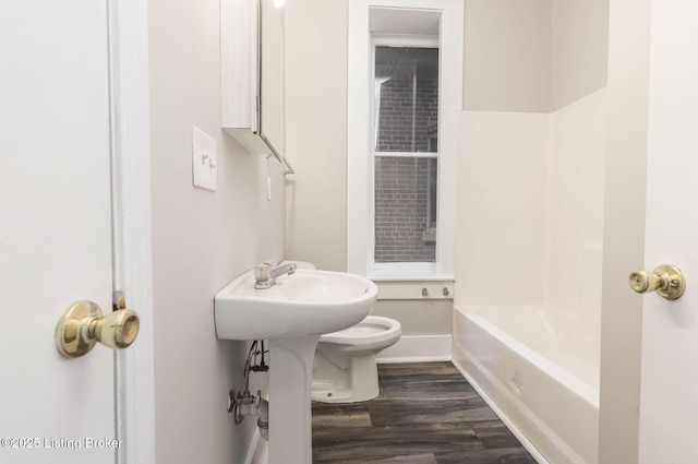 bathroom featuring hardwood / wood-style floors, toilet, and a tub to relax in