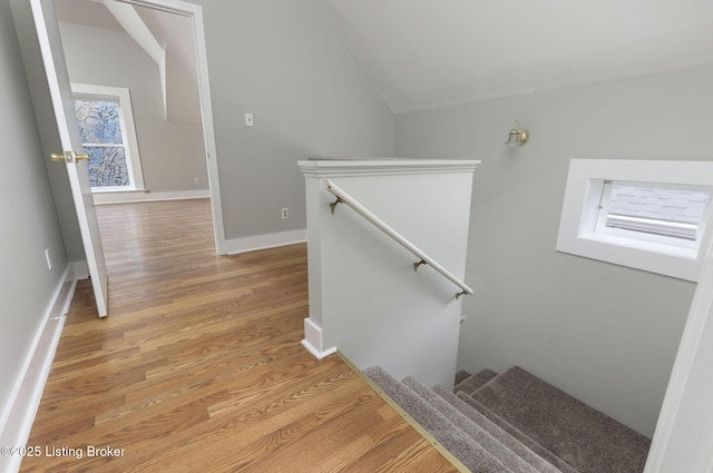 stairs featuring wood-type flooring and vaulted ceiling