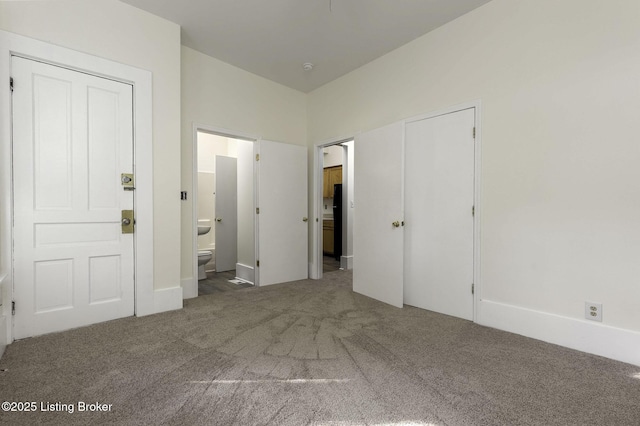 unfurnished bedroom featuring dark colored carpet and connected bathroom