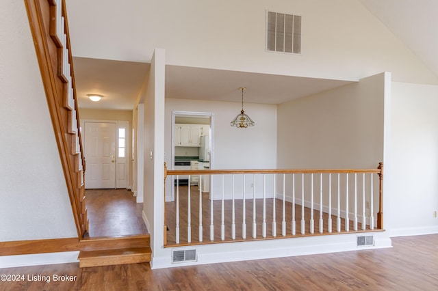 hallway with hardwood / wood-style flooring and vaulted ceiling