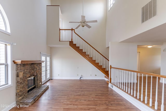 unfurnished living room with a fireplace, hardwood / wood-style floors, a towering ceiling, and ceiling fan