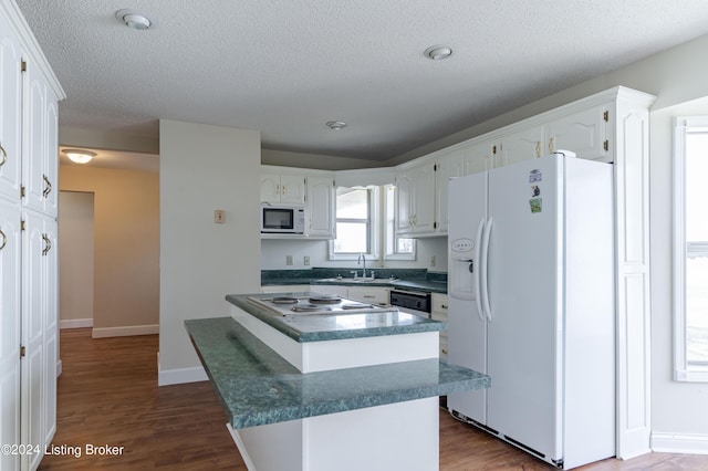 kitchen featuring a textured ceiling, white appliances, sink, hardwood / wood-style flooring, and white cabinets