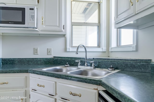 kitchen featuring dishwasher, white cabinetry, sink, and white microwave