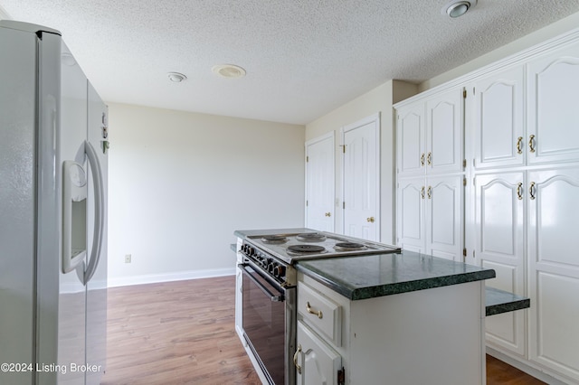 kitchen with a kitchen island, refrigerator with ice dispenser, light hardwood / wood-style floors, stainless steel range with electric stovetop, and white cabinets