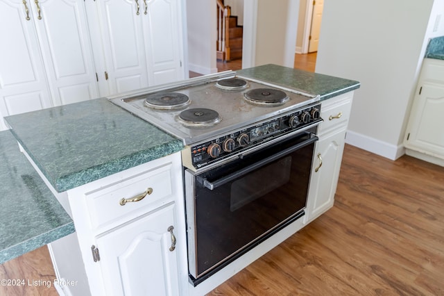 kitchen featuring light wood-type flooring, electric range, white cabinetry, and a kitchen island