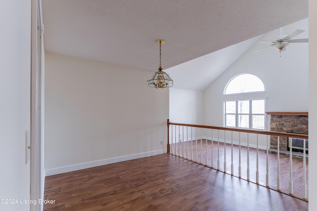 unfurnished room with ceiling fan with notable chandelier, dark wood-type flooring, and lofted ceiling