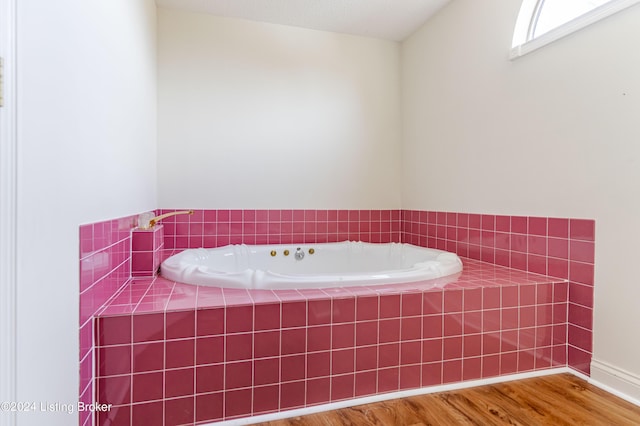 bathroom with hardwood / wood-style flooring and tiled tub